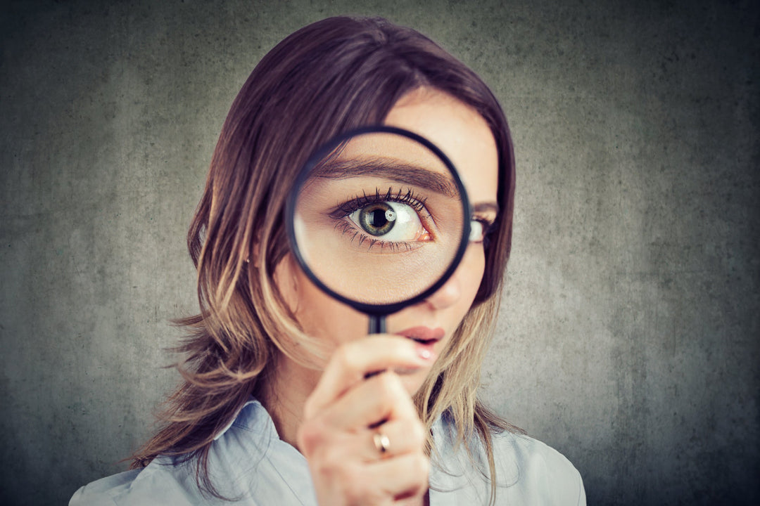 Woman holding a magnifying glass enlarging her eye