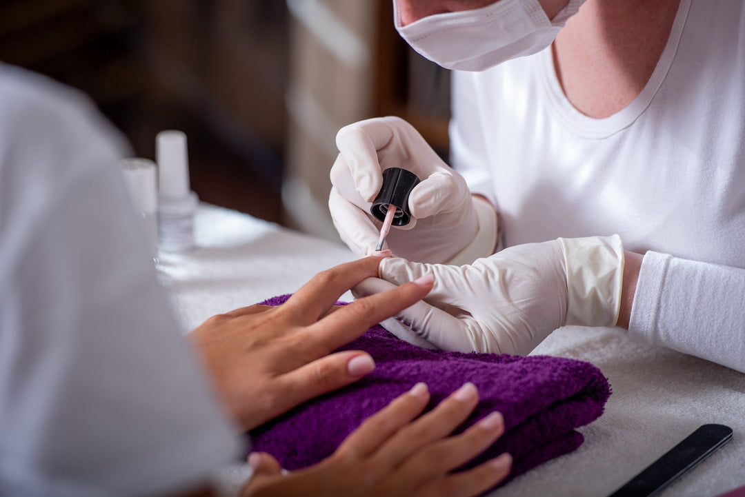 nagelprofessional die topcoat aanbrengt tijdens een manicure