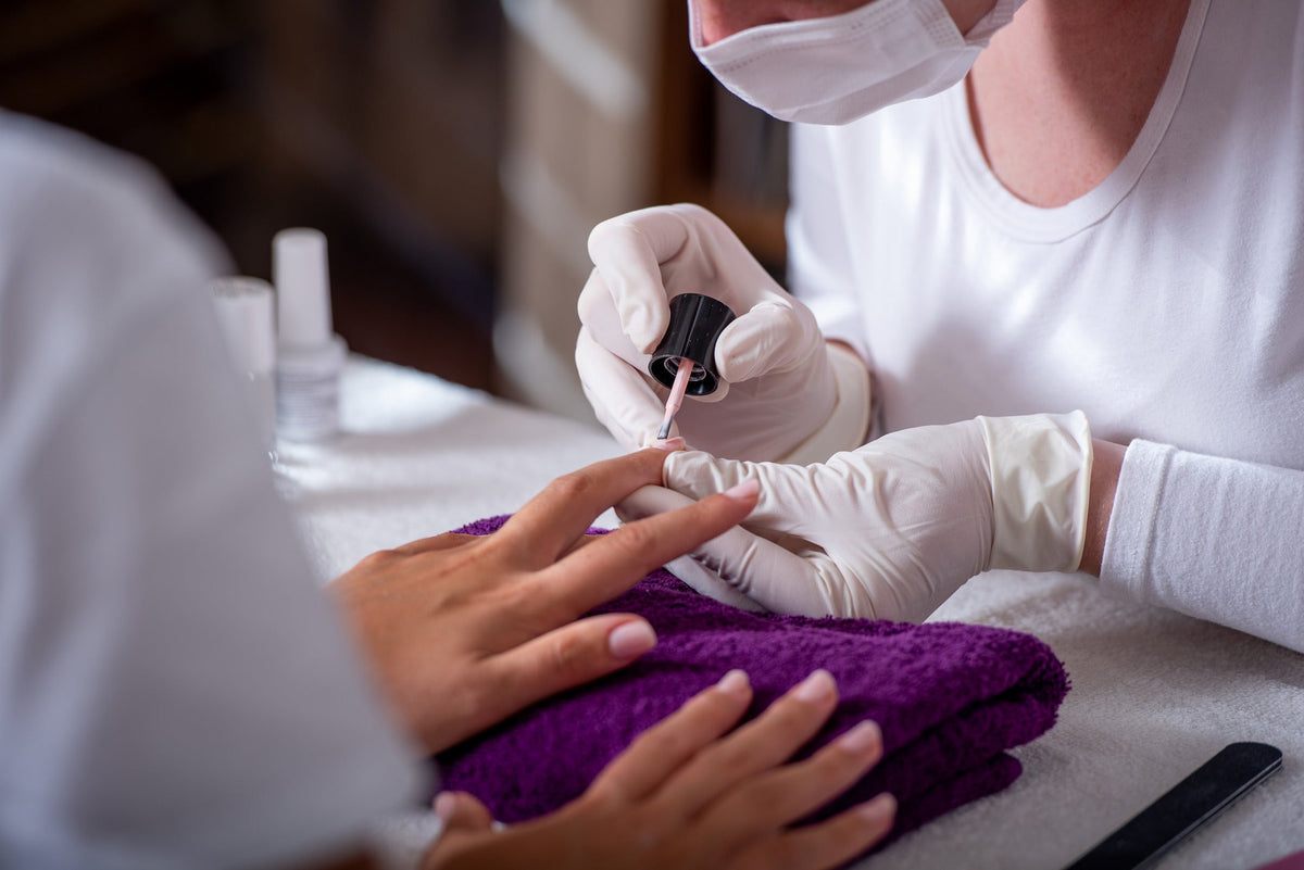 nagelprofessional die topcoat aanbrengt tijdens een manicure