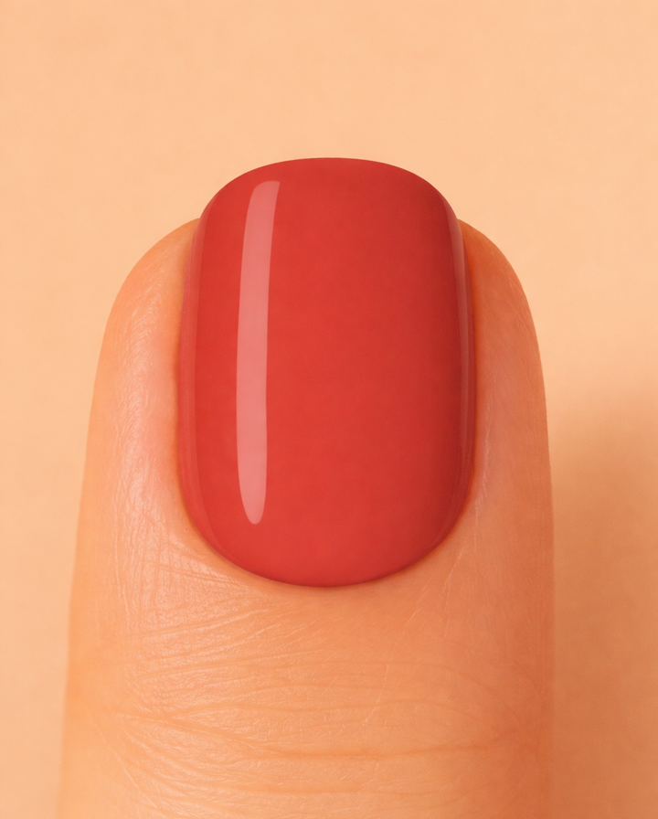 Nail with red polish on a peach background