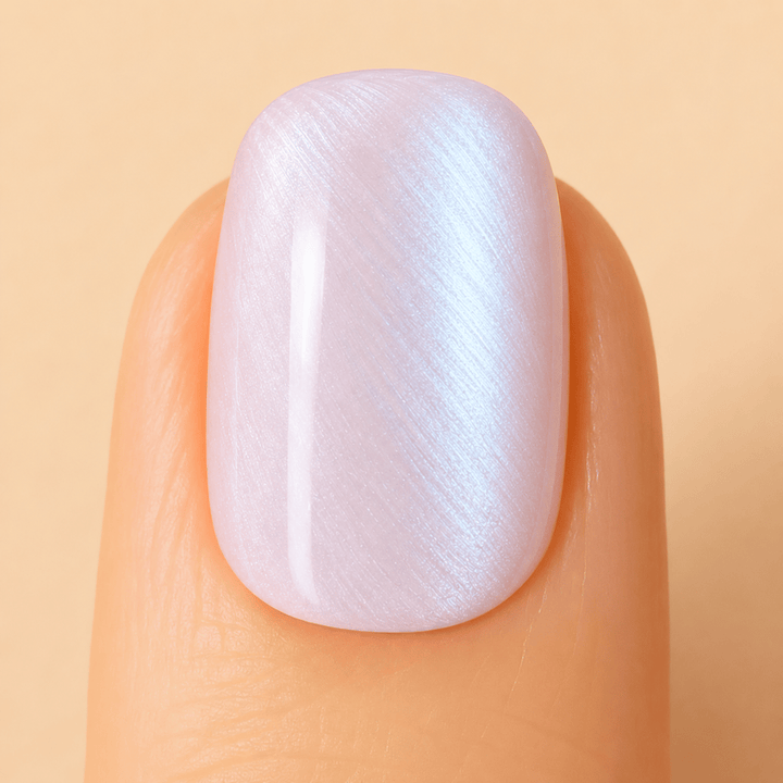A close-up of a fingernail with a glossy, transparent white manicure featuring a subtle iridescent shimmer.