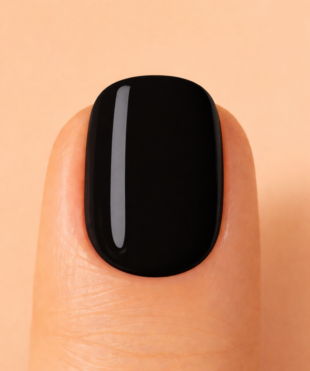 Black nail polish on a finger against a beige background
