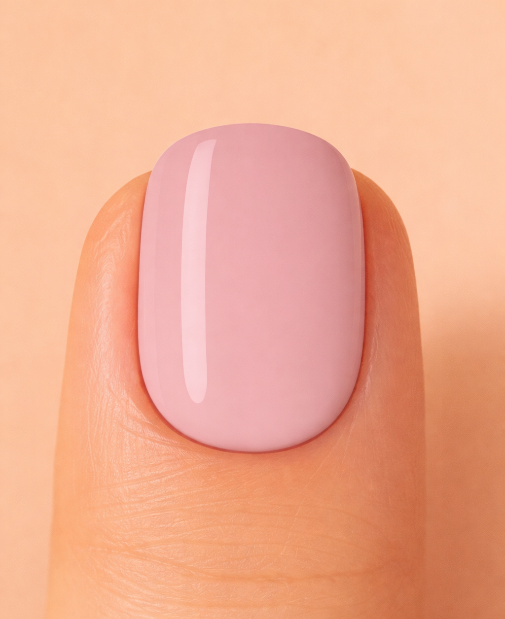 Close-up of a nude pink nail on a peach-coloured background