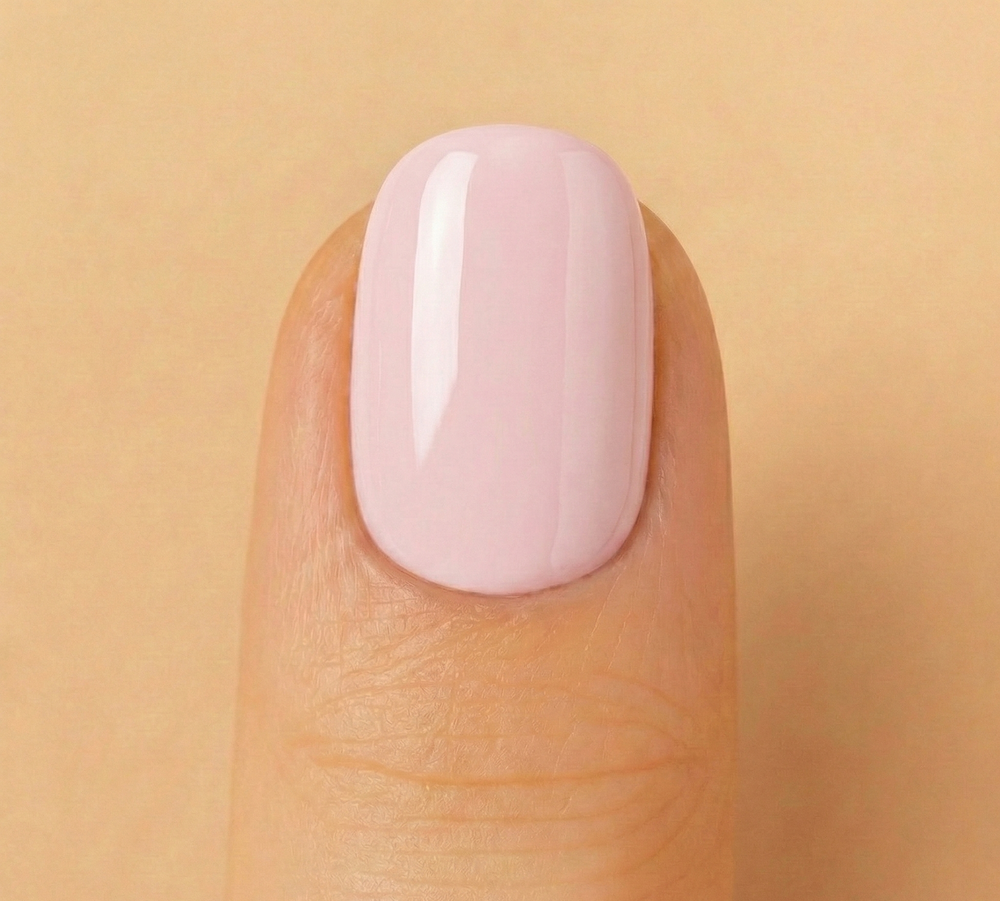 Close-up of a finger with a light pink nail on a beige background